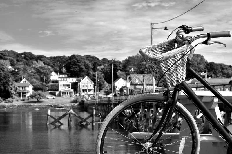 A quaint looking bike with a basket leaning against a picnic table with a boardwalk in the background