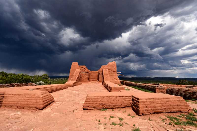 A pueblo with a dark storm brewing behind it