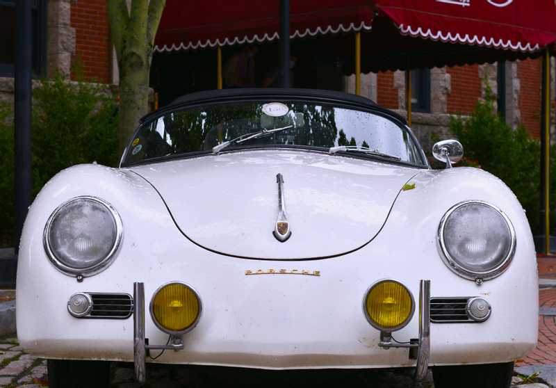 An old Porsche sits in front of a hotel