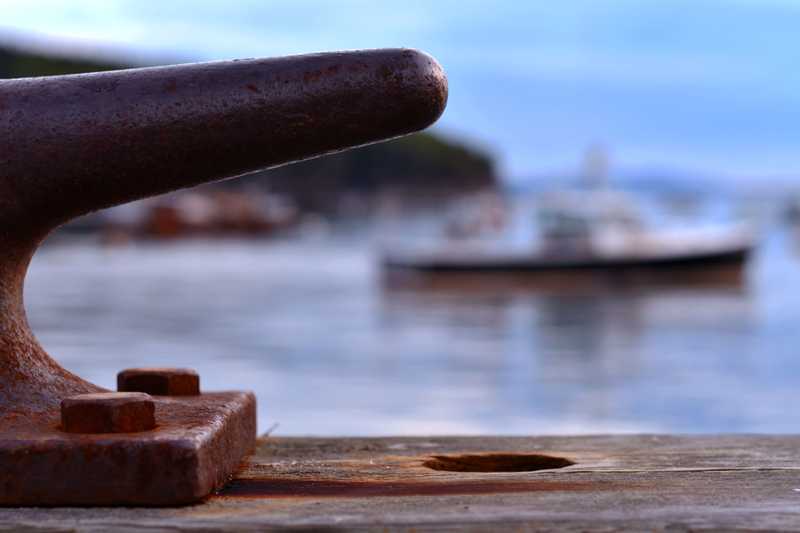 A shot focused on half of a boat anchor with a boat blurred in the background