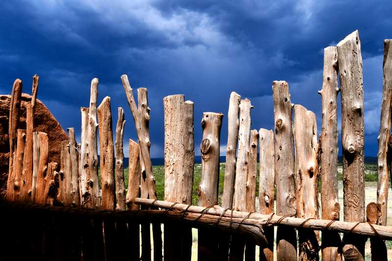 Rustic fence inside pueblo overlooking brewing storm