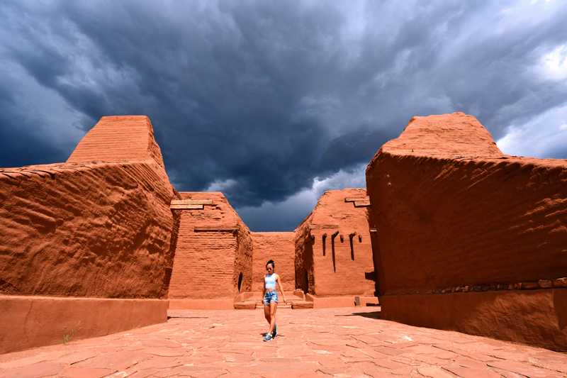 Woman in the entrance of a pueblo just outside of Santa Fe with a looming storm in the background